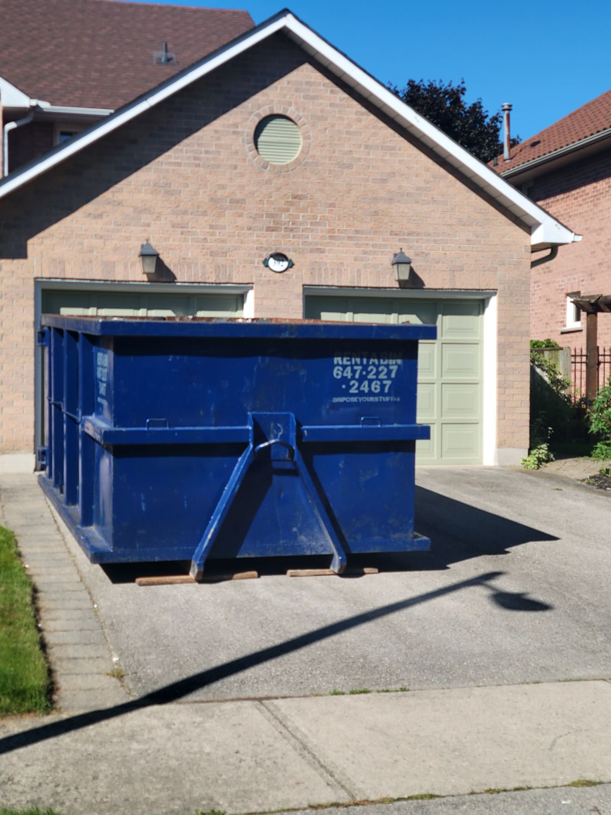 Crew measuring curb clearance for a dumpster in Oakville