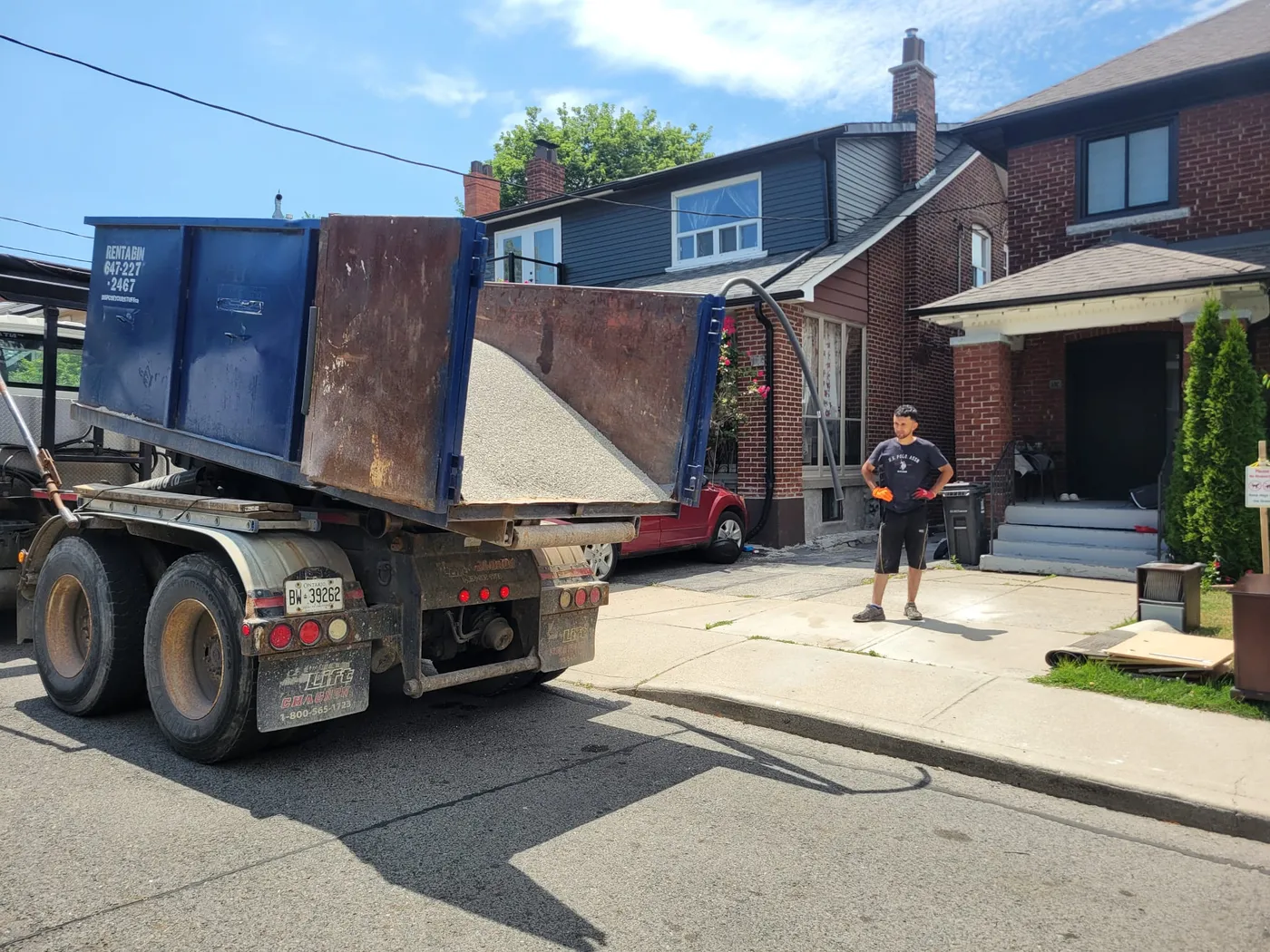 Blue disposal truck tipping its bin in a residential area