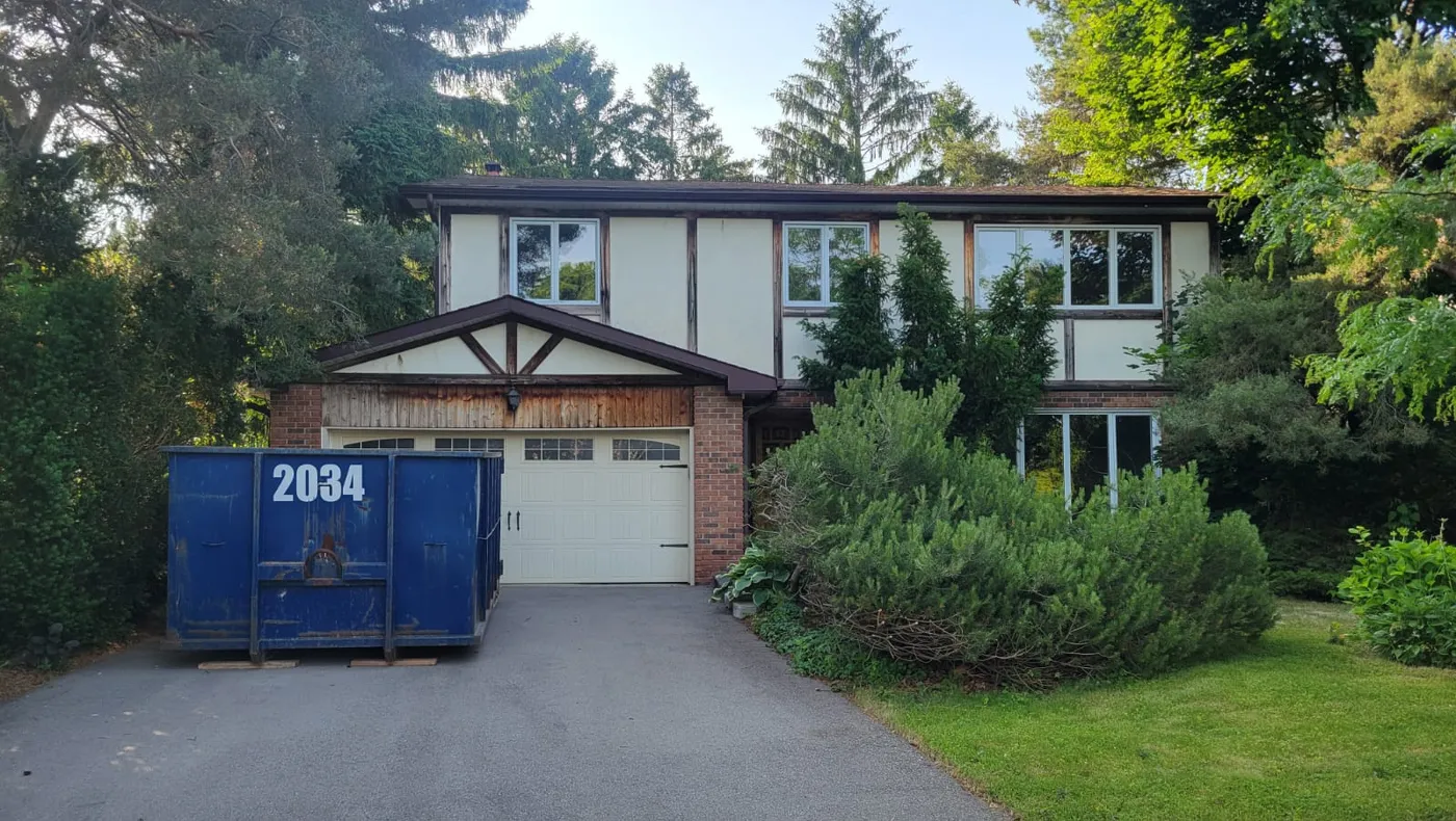 Blue residential disposal bin sits on an asphalt driveway