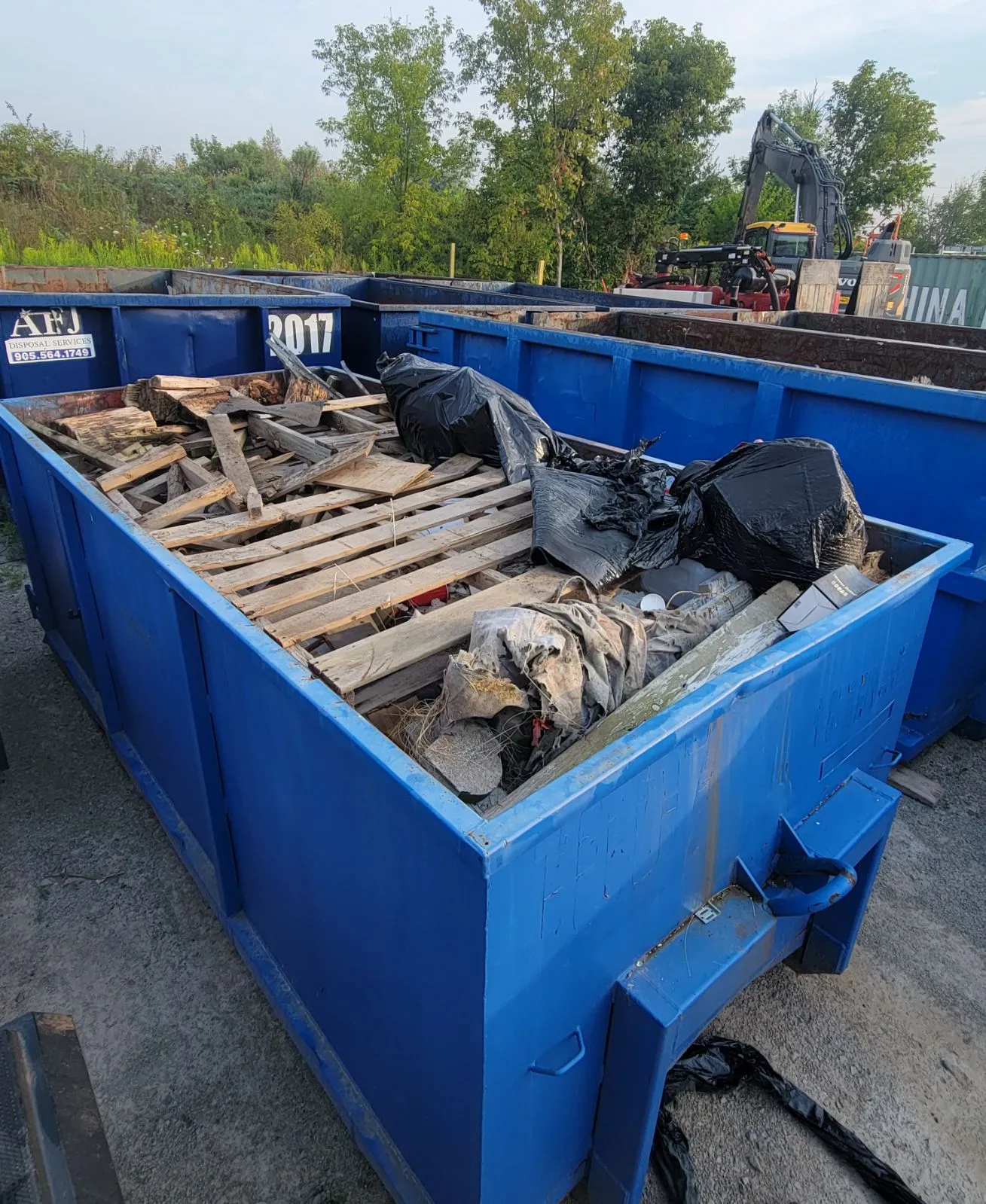 Close up of a 14 yard blue disposal bin filled with construction debris