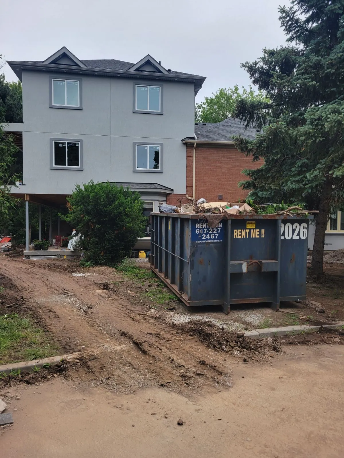 A large blue disposal bin filled with renovation waste on a site.