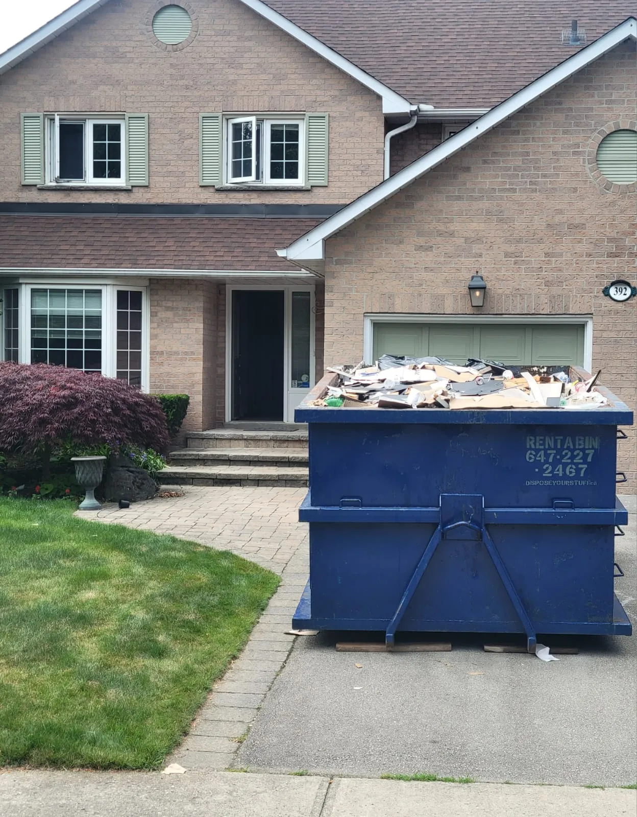 Large blue disposal bin loaded with renovation debris showing fill level
