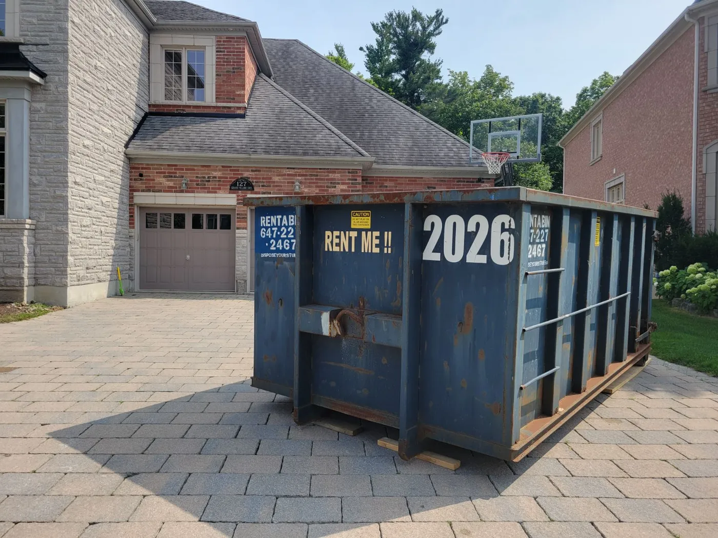 A vibrant blue disposal bin positioned on a paved driveway in a North York neighborhood.