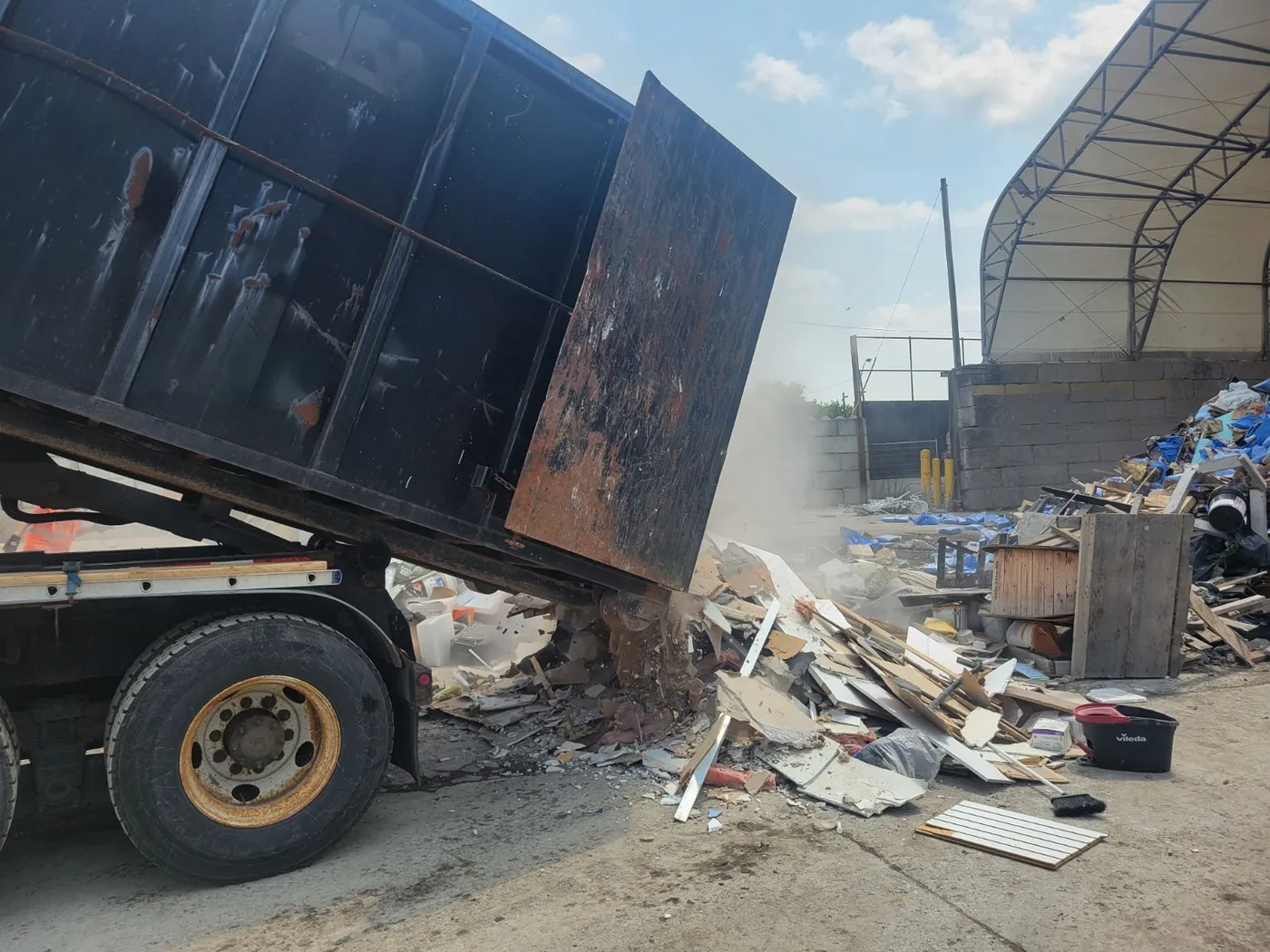 Roll-off truck unloading mixed construction and demolition debris at an outdoor processing facility