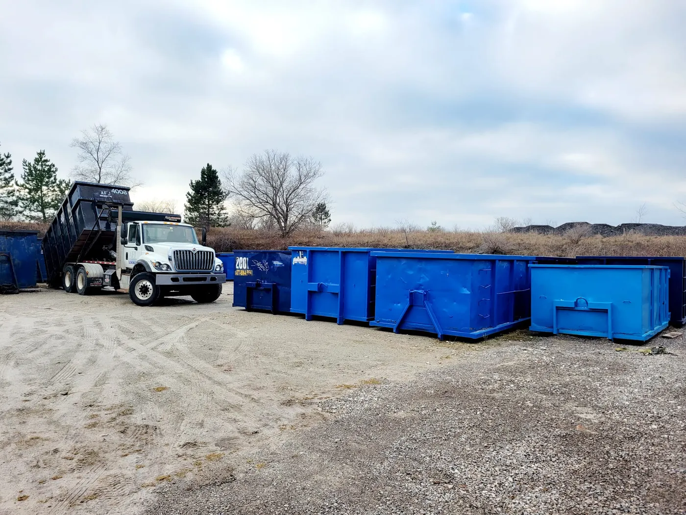 Roll-off truck positioning a disposal bin beside a residential property