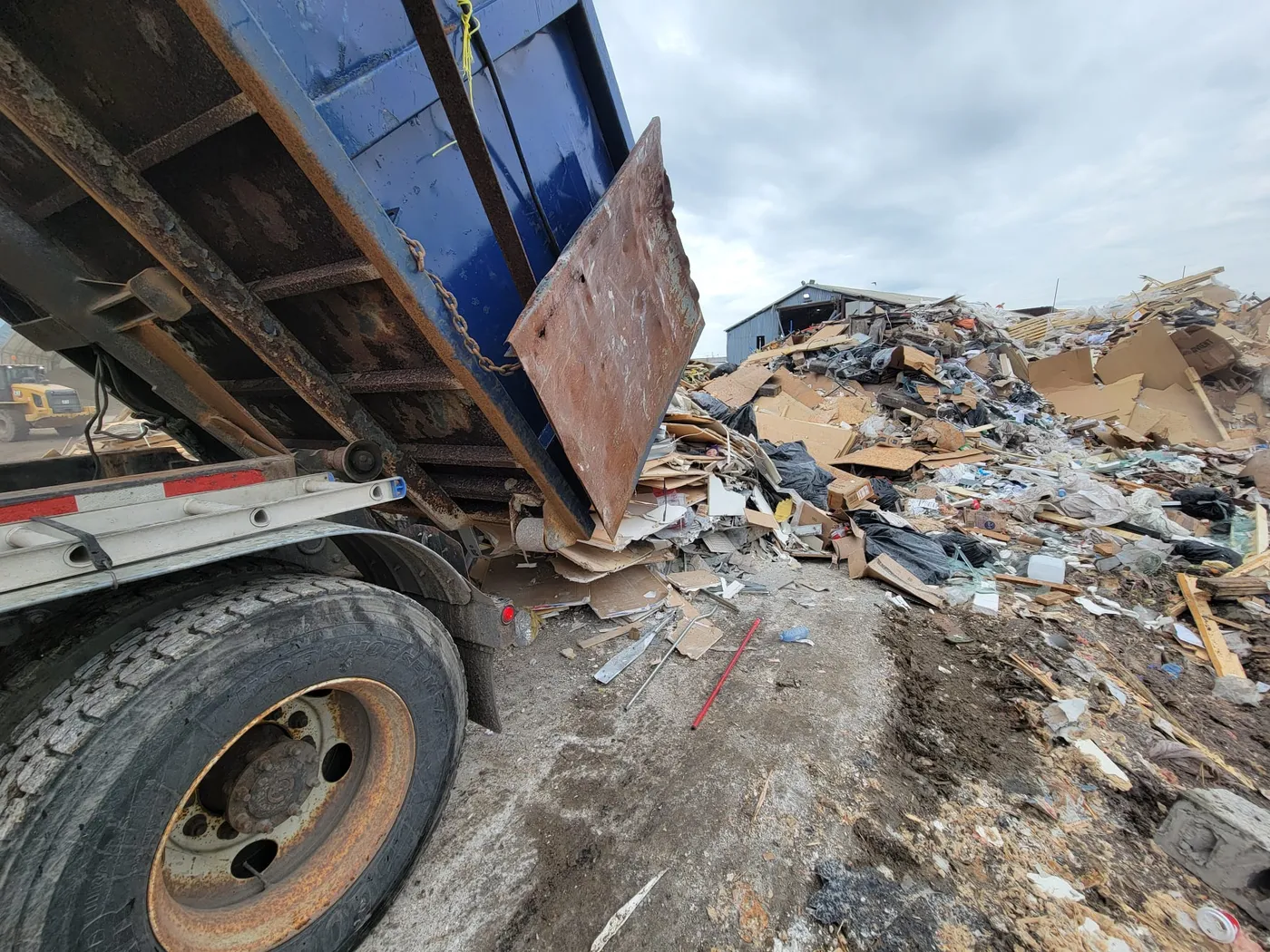 Disposal truck tipping a full bin at a licensed waste processing facility
